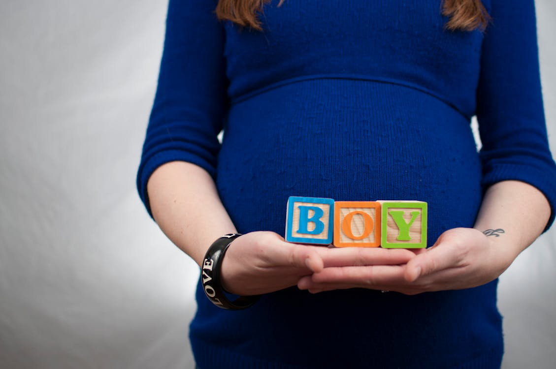 A woman holding blocks spelling boy