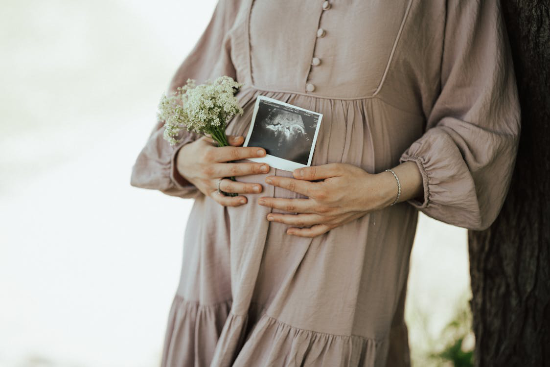A pregnant woman holding ultrasound keepsakes with flowers