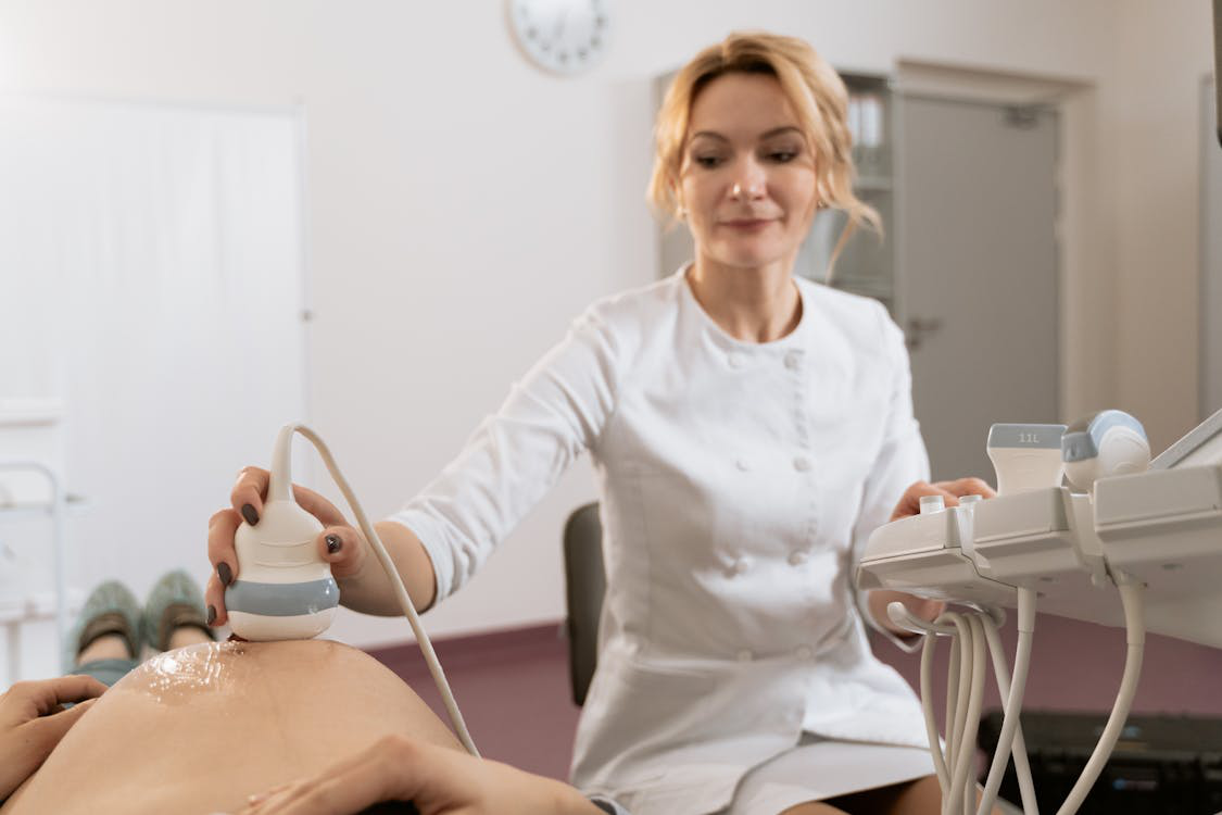 An ultrasound technician rubbing gel on the belly of an expectant mother