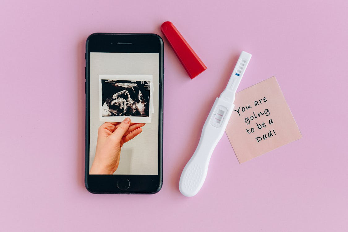 An ultrasound image with a pregnancy test kit and a note for dad-to-be