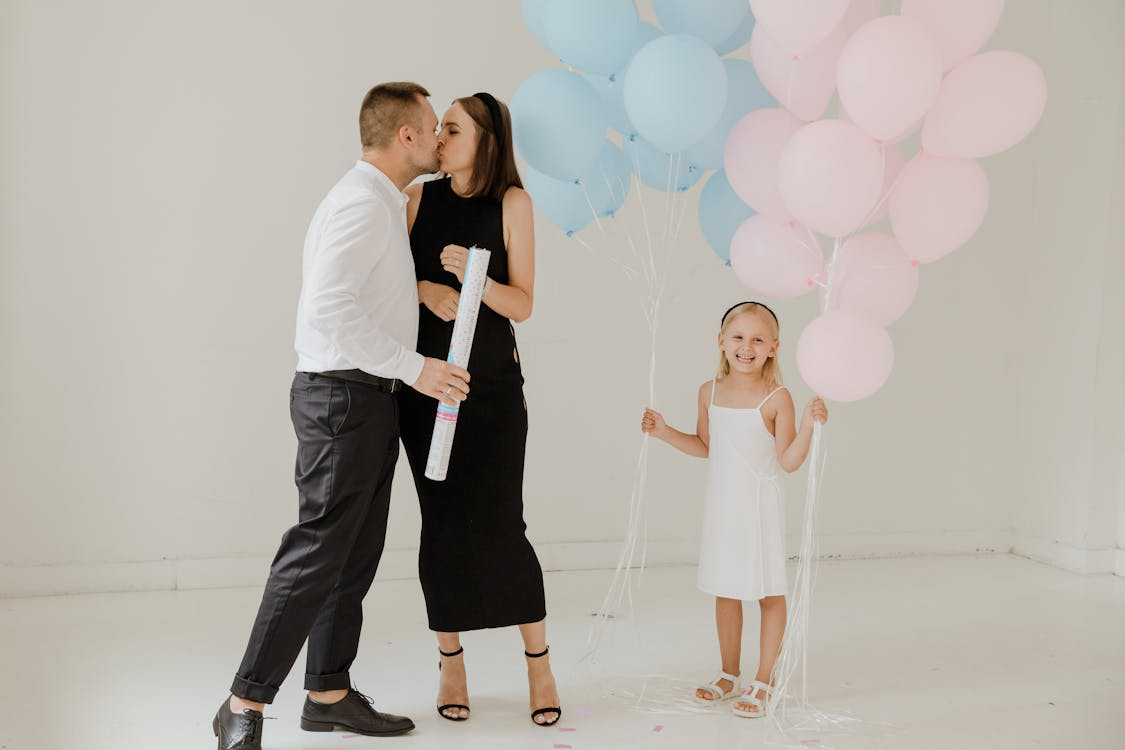 An expectant couple at their gender reveal party with their daughter