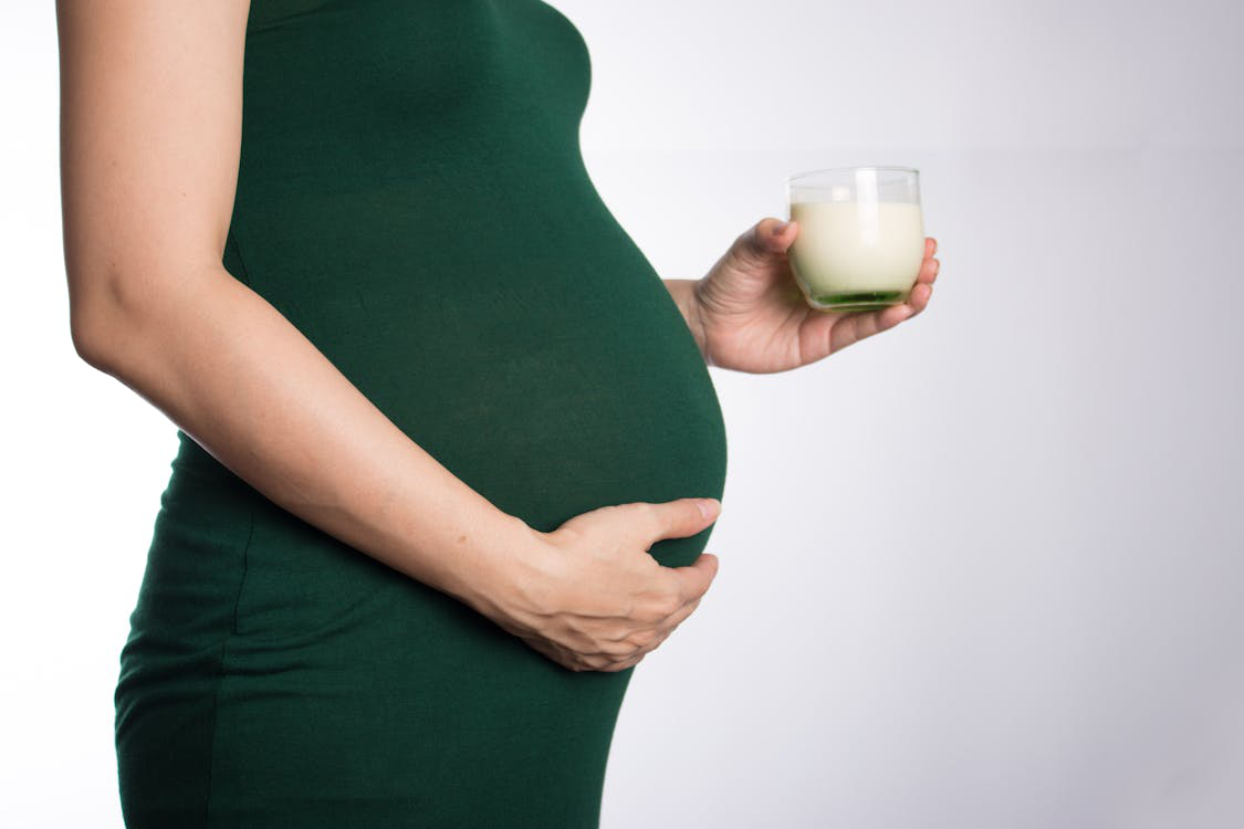 A pregnant woman holding a glass of milk