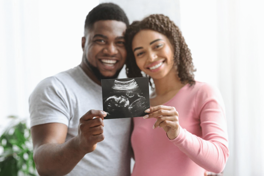A smiling couple holding their child’s ultrasound image