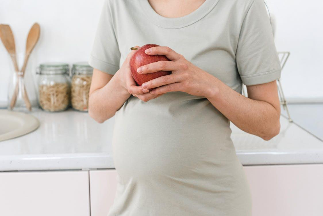 A pregnant woman holding an apple
